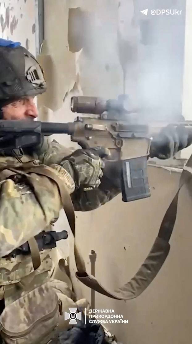 A Ukrainian soldier fires a machine gun towards enemy positions, in Avdiivka