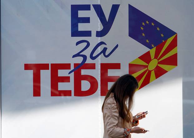 A woman passes next to posters reading "EU for you" for the referendum in Macedonia on changing the country