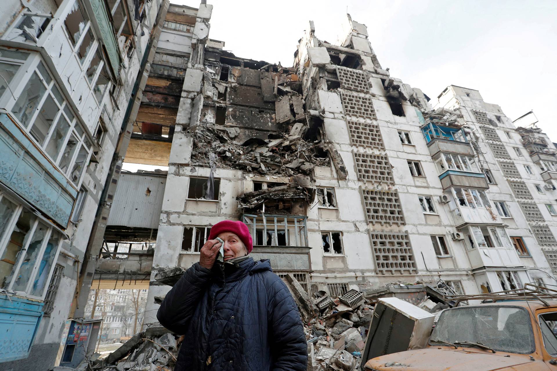 A local resident reacts next to the building where her destroyed apartment is located in the besieged city of Mariupol