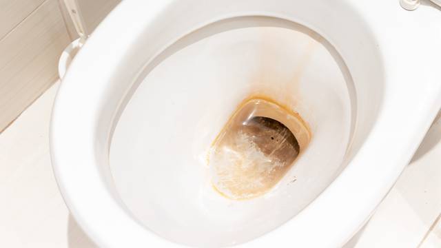 Dirty unhygienic toilet bowl with limescale stain at public restroom close up