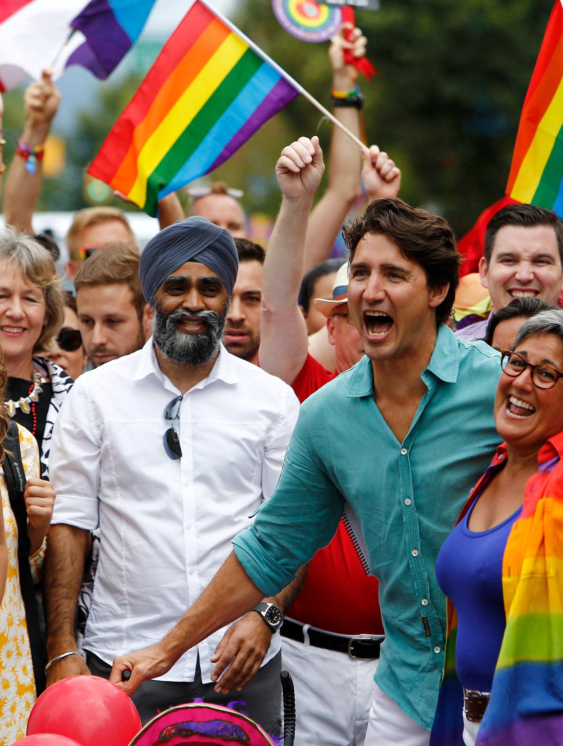 Canada's Prime Minister Justin Trudeau reacts as he and his wife Sophie GrÃ©goire Trudeau (L) walk in the Vancouver Pride Parade