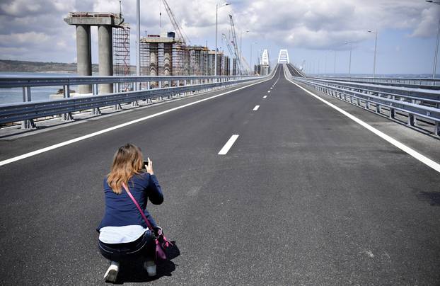 A woman takes pictures prior to a ceremony opening a bridge, which was constructed to connect the Russian mainland with the Crimean Peninsula across the Kerch Strait