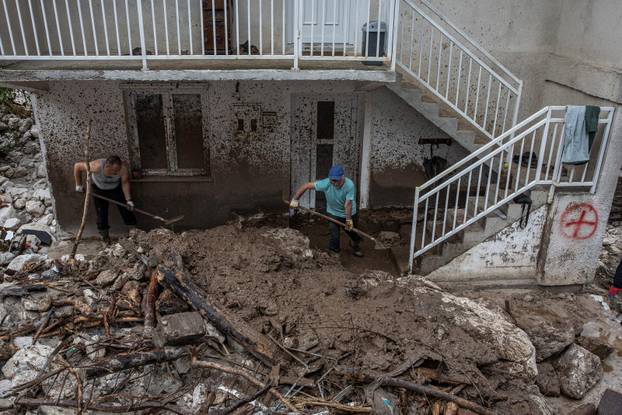 People clean debris following a landslide in the flooded village of Donja Jablanica