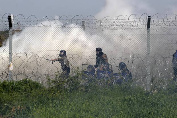 Macedonian police officers stand amid teargas smoke during clashes with protesting migrants from the Greek side of of the Greek-Macedonian border near the village of Idomeni