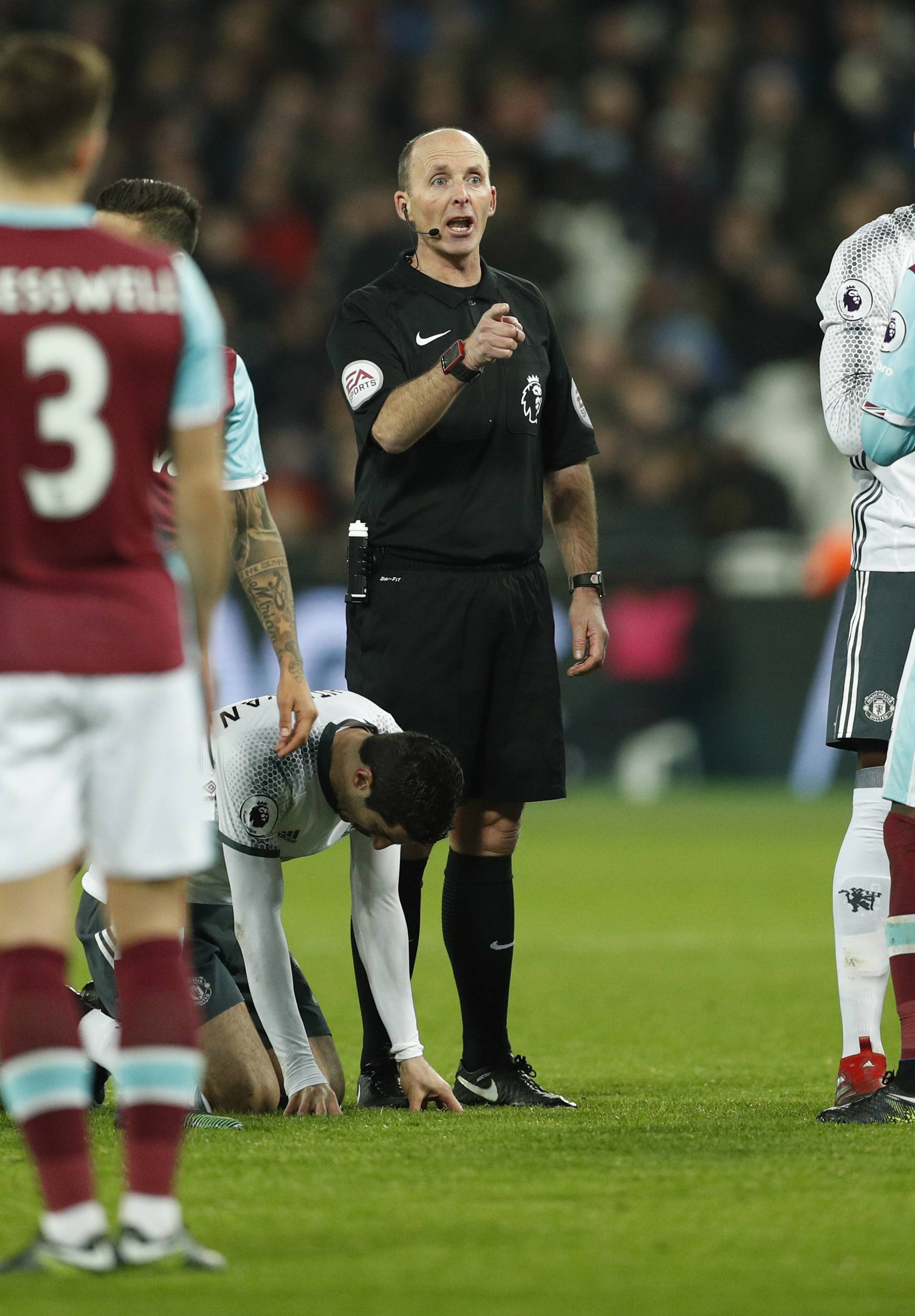 Referee Mike Dean gestures after awarding Manchester United a free kick for a foul on Henrikh Mkhitaryan