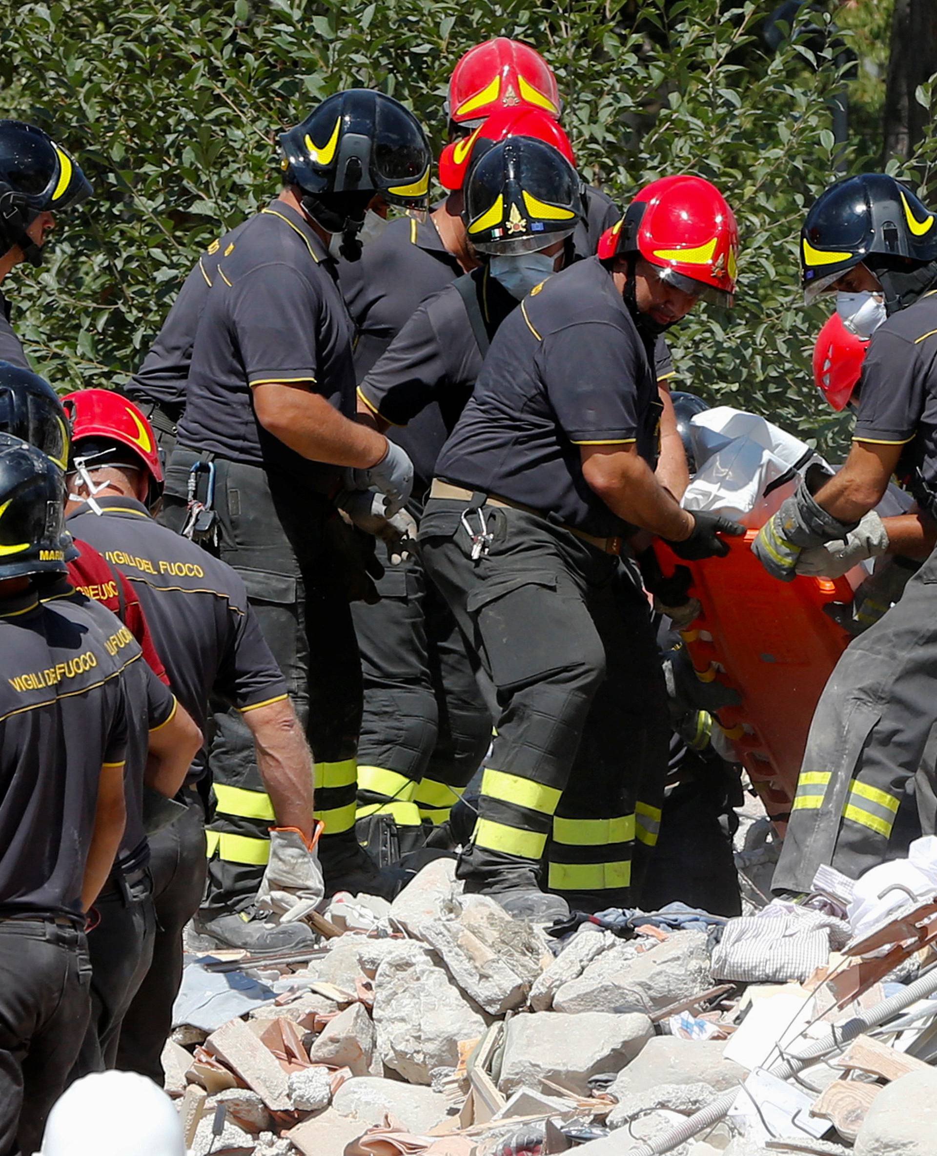 A body is carried away by rescuers following an earthquake in Amatrice