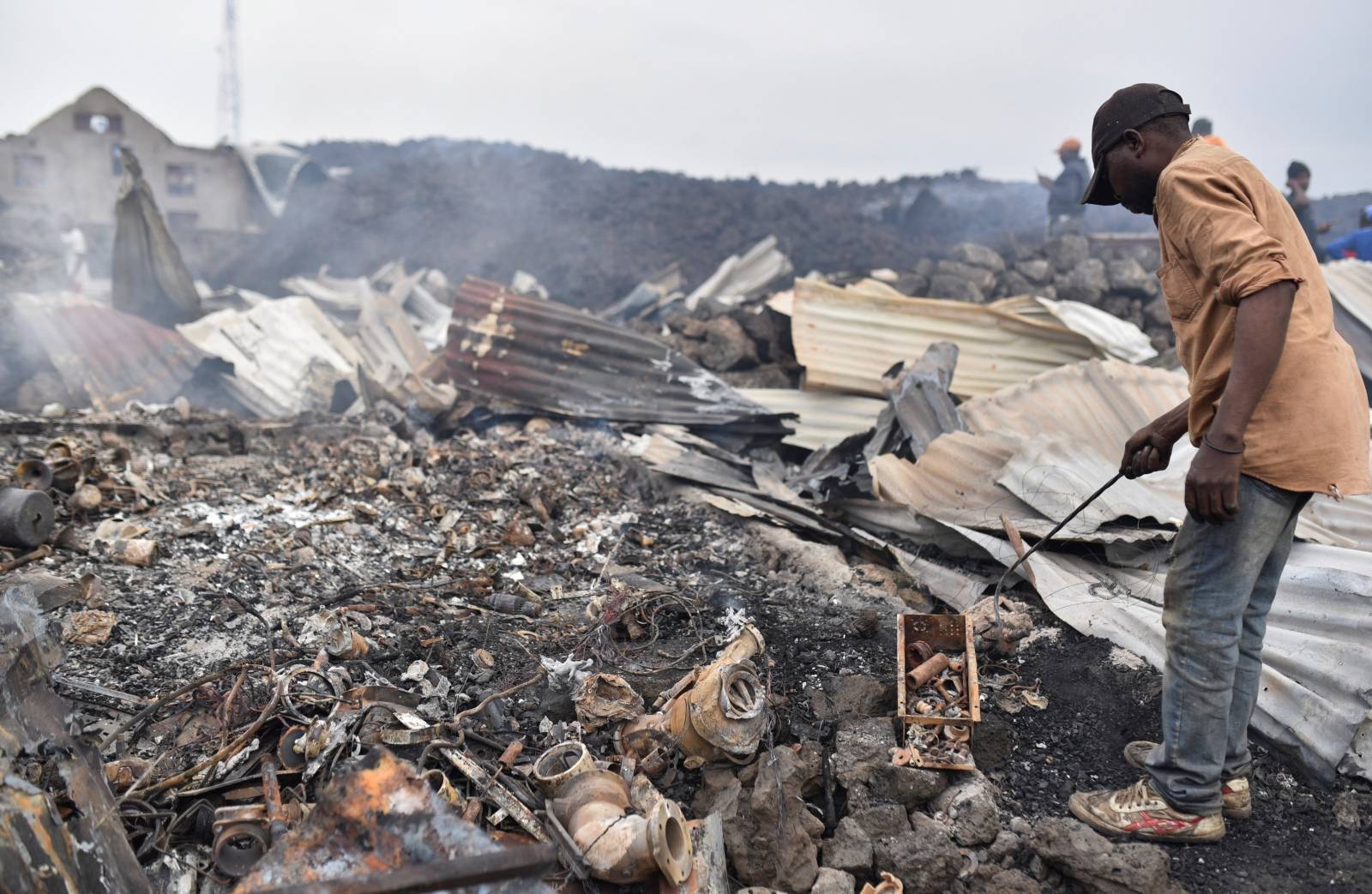 Residents pick up remains of their destroyed homes from the smouldering lava deposited by the eruption of Mount Nyiragongo volcano near Goma