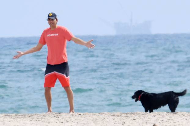 EXCLUSIVE: Mila Kunis hits the beach wearing a T-shirt that reads "Girls Kick Ass" while Ashton Kutcher sports a bright orange Peloton shirt