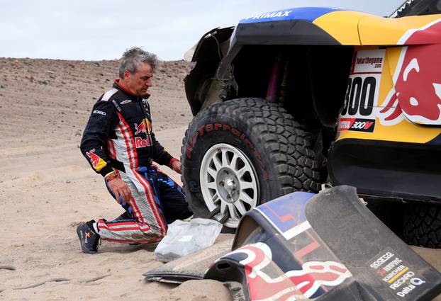 Driver Carlos Sainz, of Spain, works on his Mini after it broke down during the third stage of the Dakar Rally between San Juan de Marcona and Arequipa, Peru