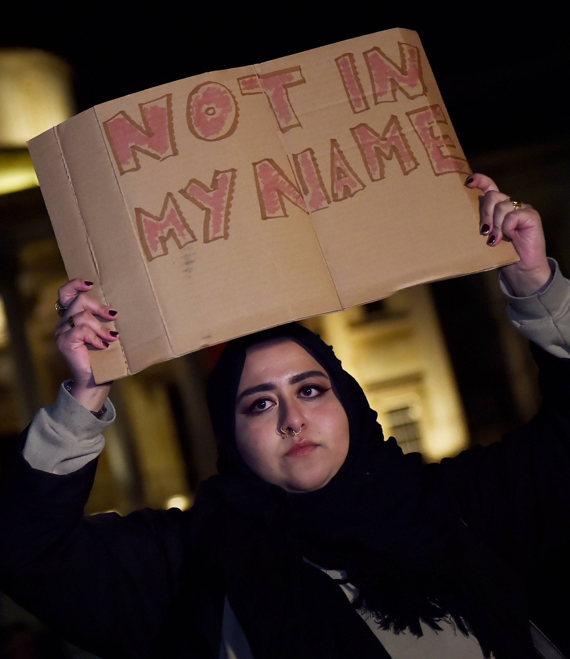 A woman holds a placard at a vigil in Trafalgar Square the day after an attack in London