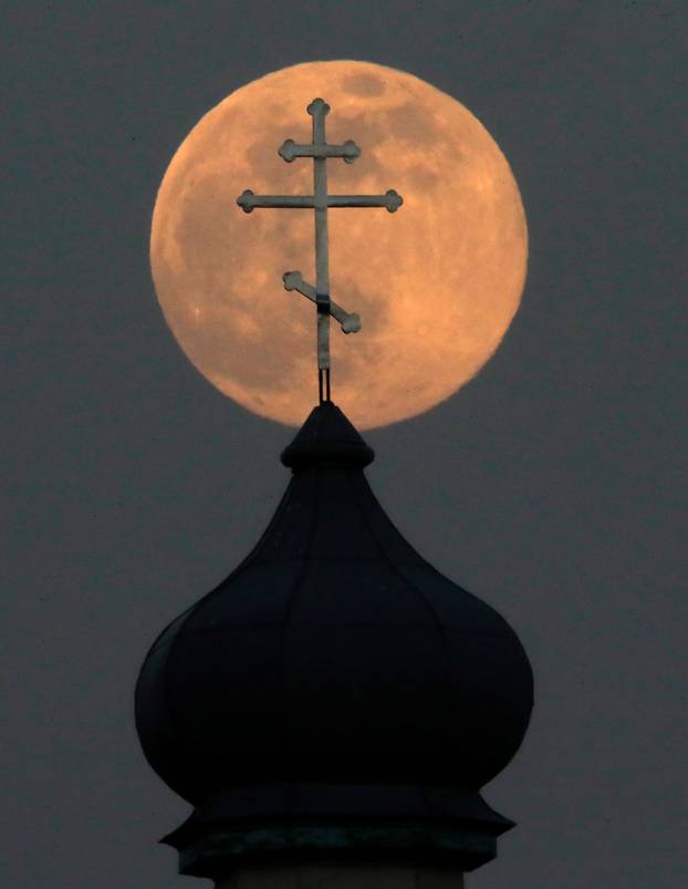 A Pink Supermoon rises behind an Orthodox Church in the village of Turets