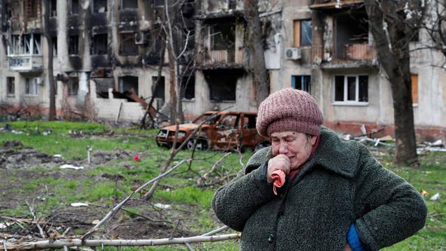 Local resident Tamara cries in front of a destroyed apartment building in Mariupol