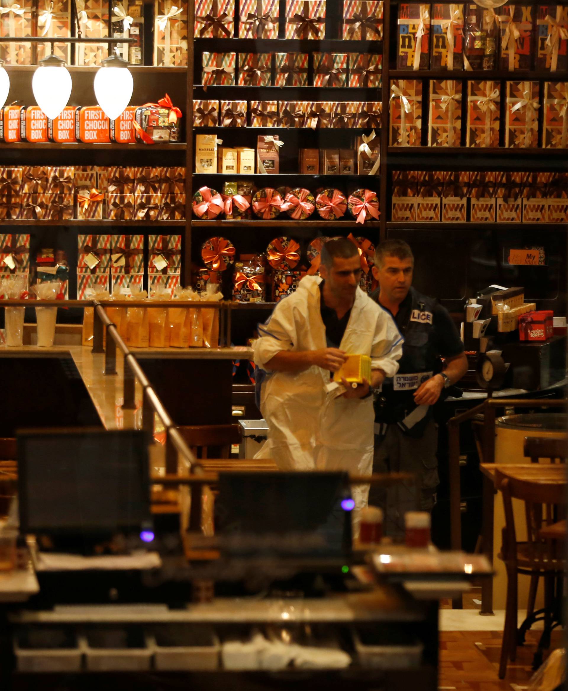 Israeli policemen work inside a restaurant following a shooting attack in the center of Tel Aviv