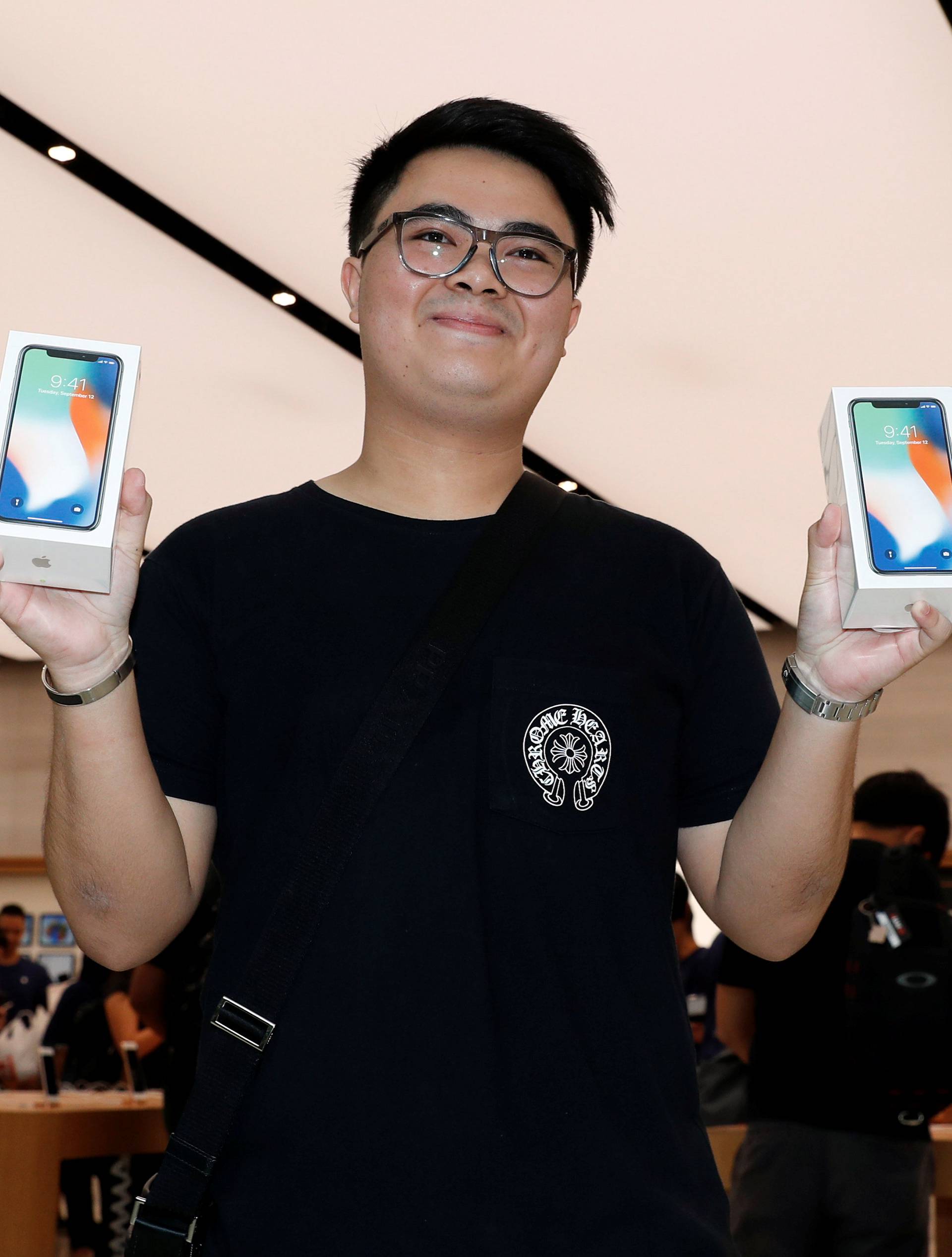 One of the first customers, Mod, 22 of Bangkok poses with his iPhone X during its launch at the Apple store in Singapore