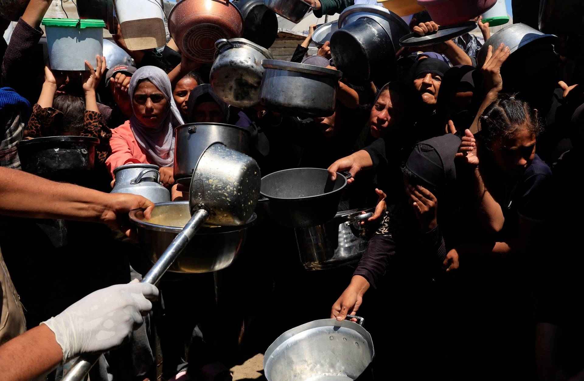 Palestinians wait to receive food from a charity kitchen, amid a hunger crisis, in Khan Younis