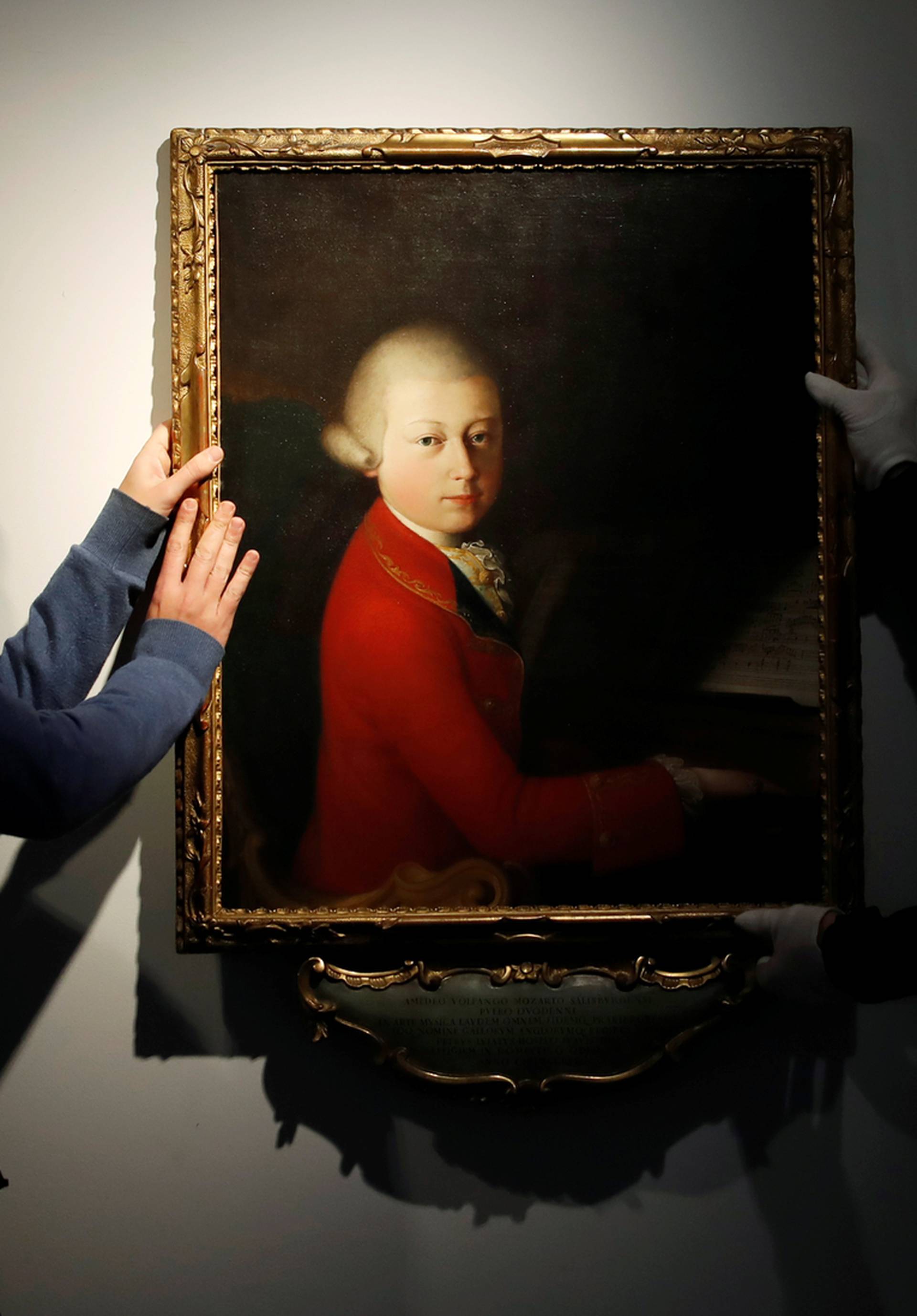 Workers install a portrait due to be sold at auction by Christie's in Paris which depicts composer Wolfgang Amadeus Mozart