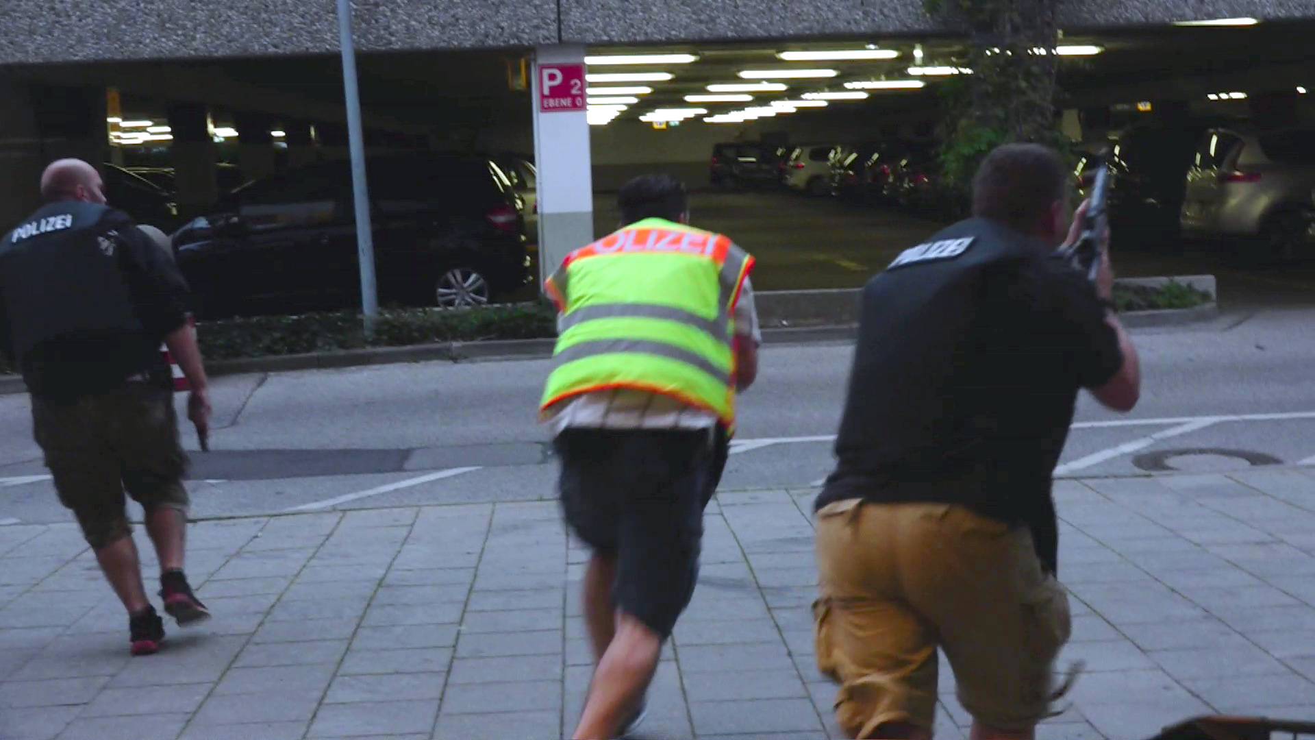 Screen grab shows plain clothes police officers running towards car park of shopping mall during shooting rampage in Munich