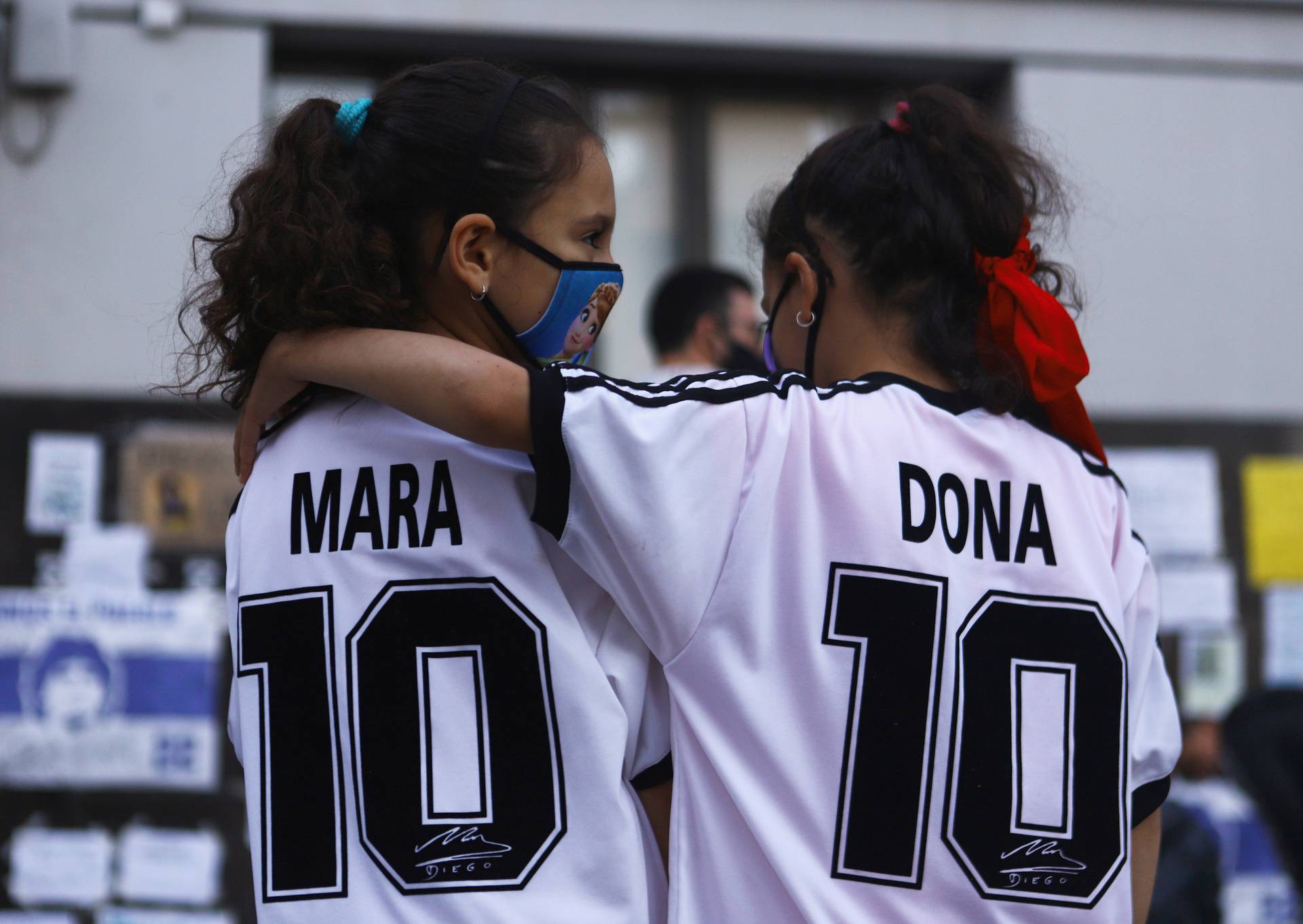 Twin sisters Mara and Dona Rotundo, fans of Argentine soccer great Diego Maradona and who are named after him, embrace outside the clinic where Maradona underwent brain surgery, in Olivos