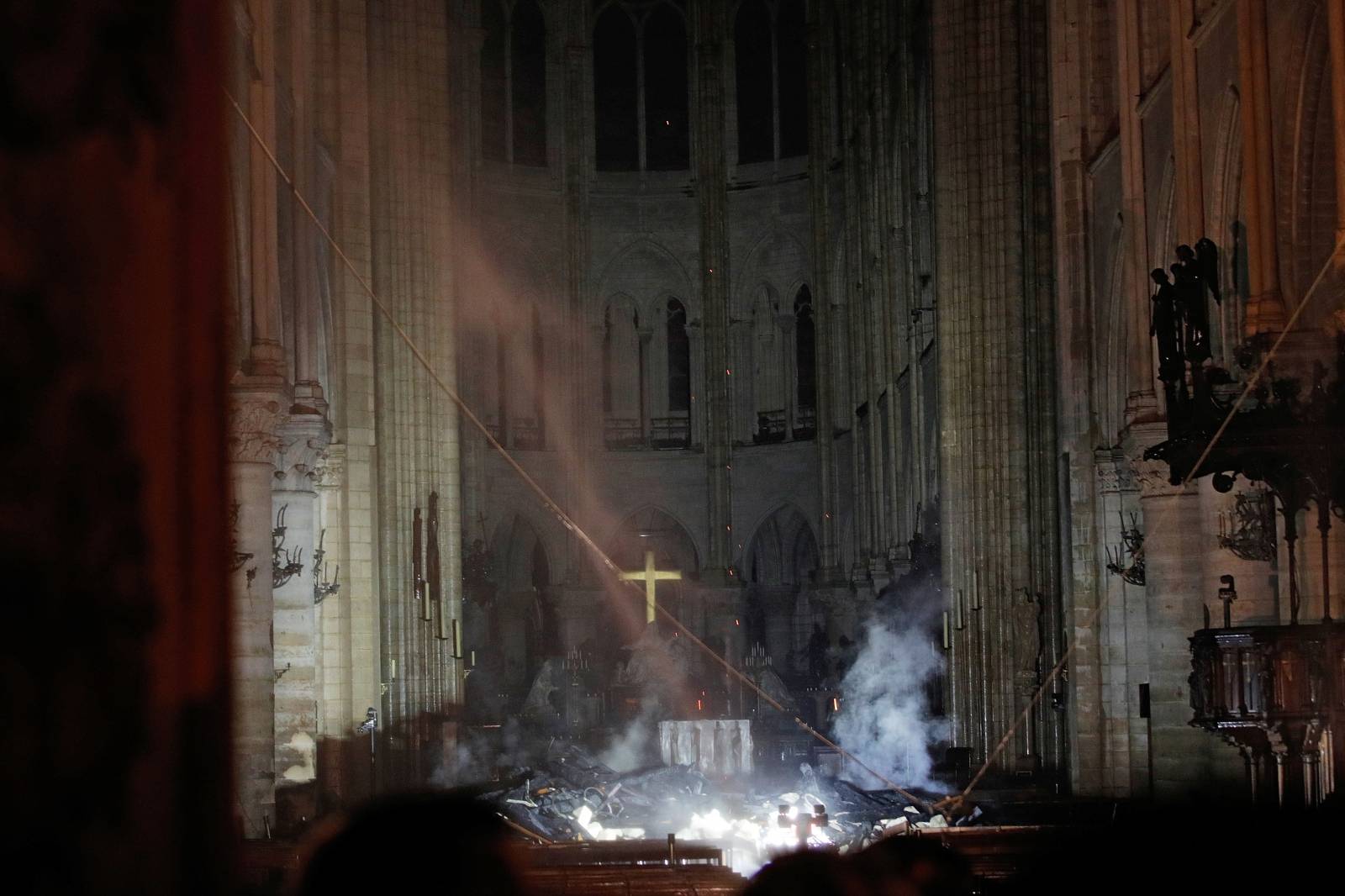 Smoke rises around the altar in front of the cross inside the Notre Dame Cathedral as a fire continues to burn in Paris