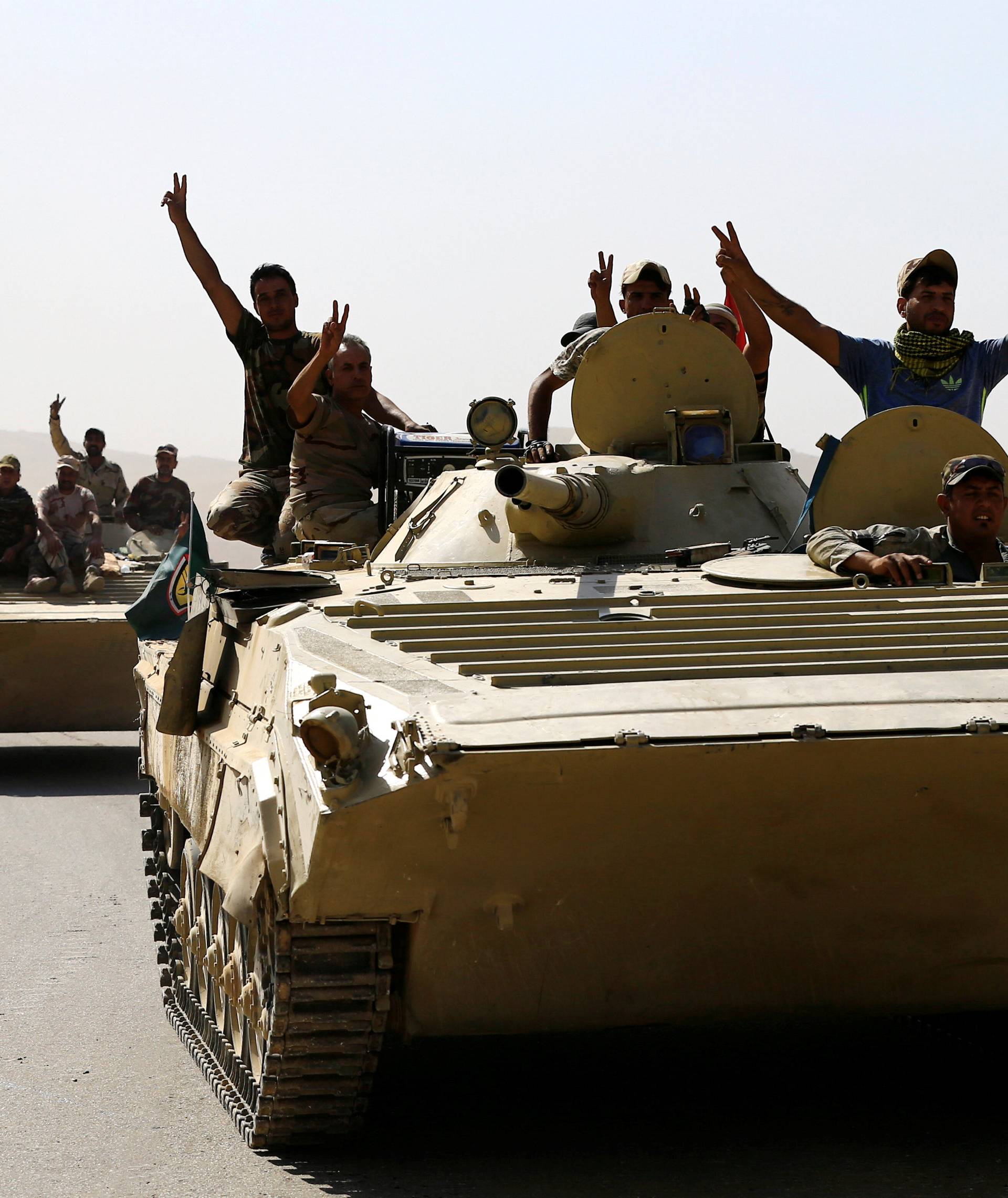 Members of Iraqi Army ride a military vehicle during the war between Iraqi army and Shi'ite Popular Mobilization Forces (PMF) against the Islamic State militants in al-'Ayadiya, northwest of Tal Afar