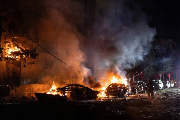 An Israeli firefighter works to put out a fire on a car at the site of a projectile impact, in Tel Aviv
