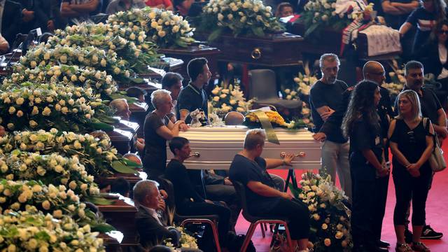 A relative touches the coffin during the state funeral of the victims of the Morandi Bridge collapse, at the Genoa Trade Fair and Exhibition Centre in Genoa