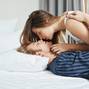 Romantic shot of tender and beautiful european couple in pyjamas, hugging in bed and kissing in morning. Couple found their own heaven on Earth, wanting to stay like this forever.