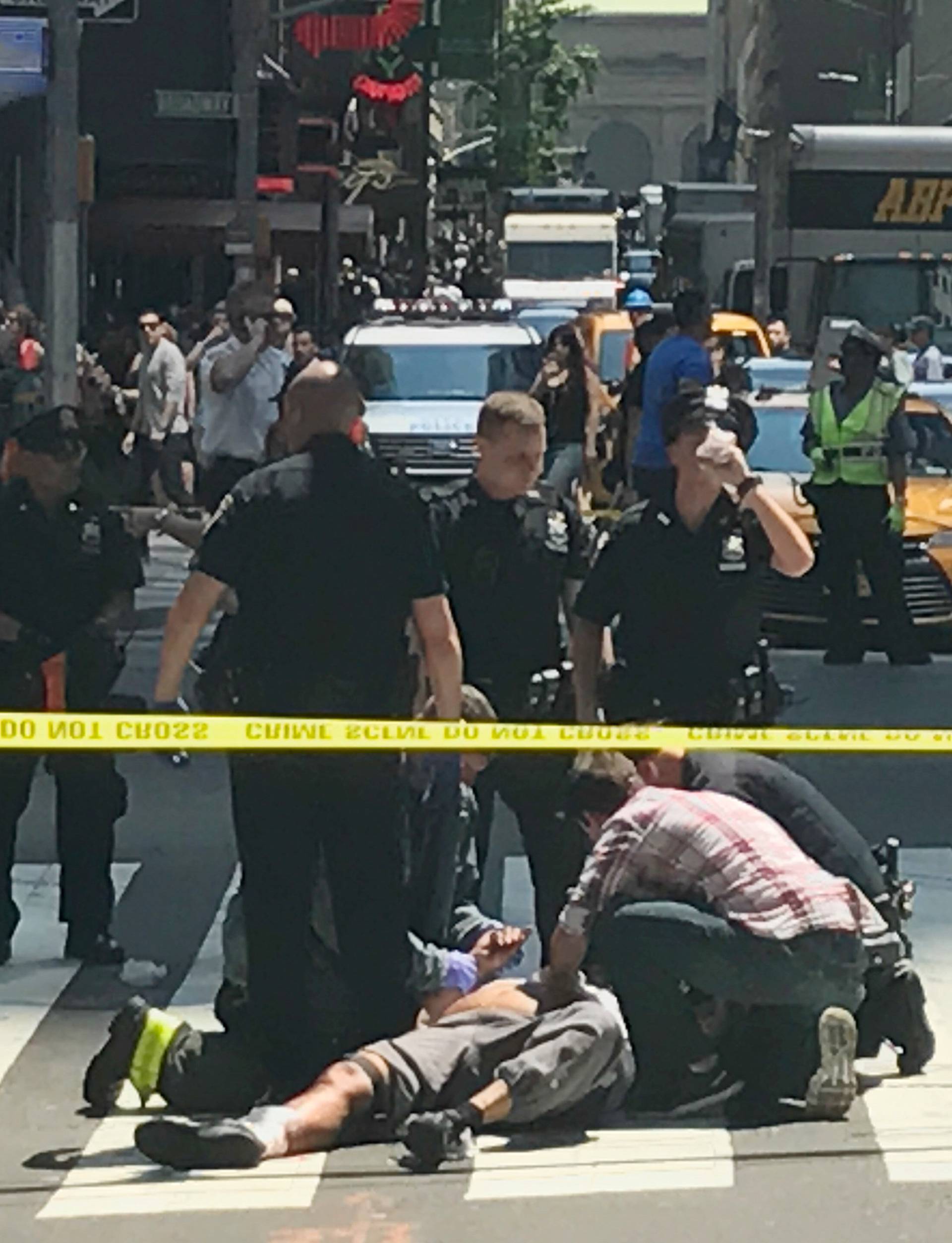 First responders and people help injured pedestrians after a vehicle struck pedestrians on a sidewalk in Times Square in New York