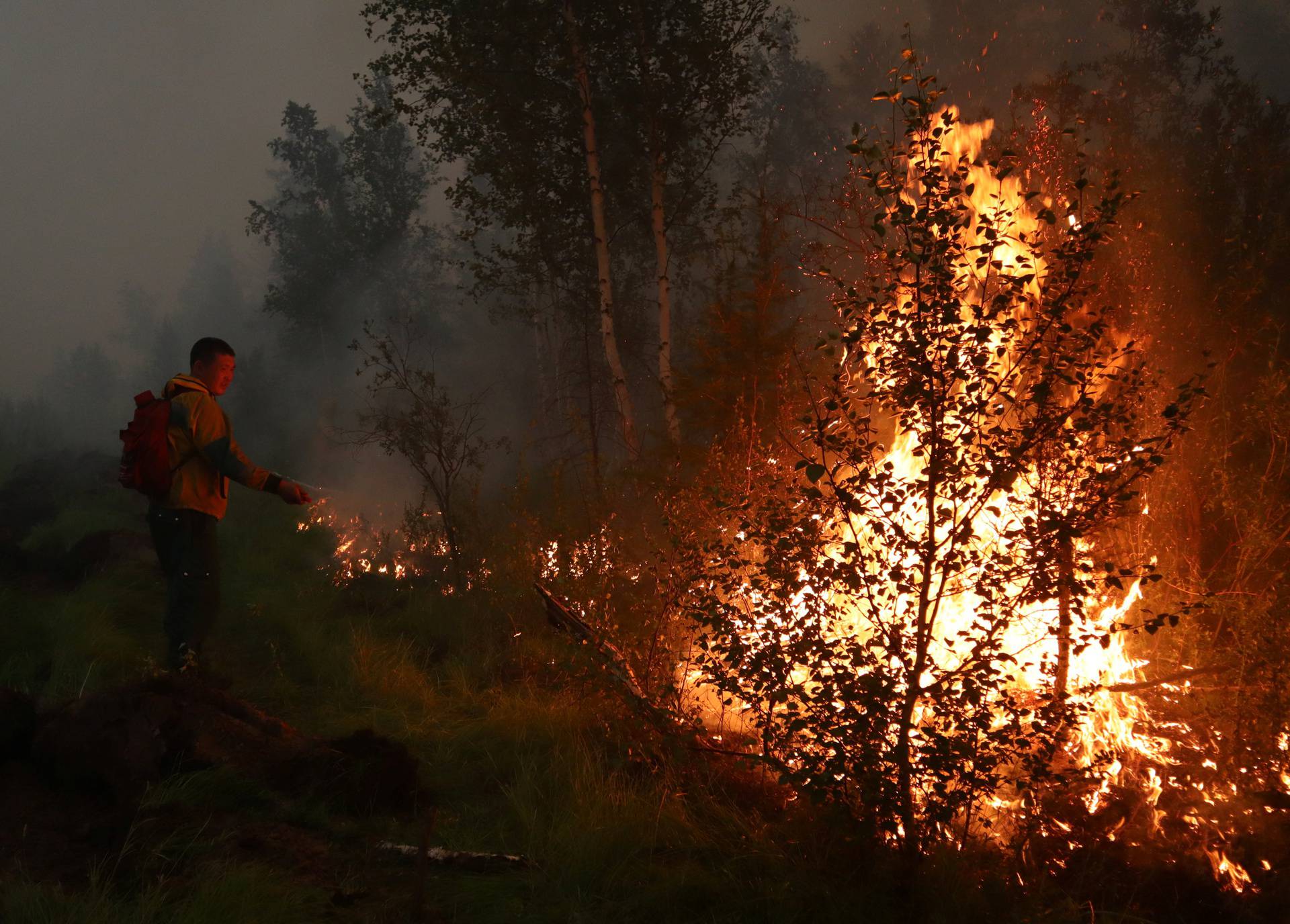 A firefighter works to extinguish a forest fire in Yakutia