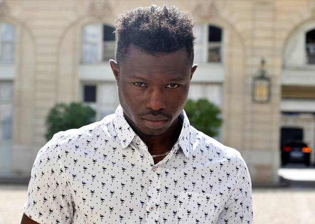 Mamoudou Gassama, 22, from Mali, displays a certificate of courage and dedication as he leaves the Elysee Palace after his meeting with French President Emmanuel Macron, in Paris