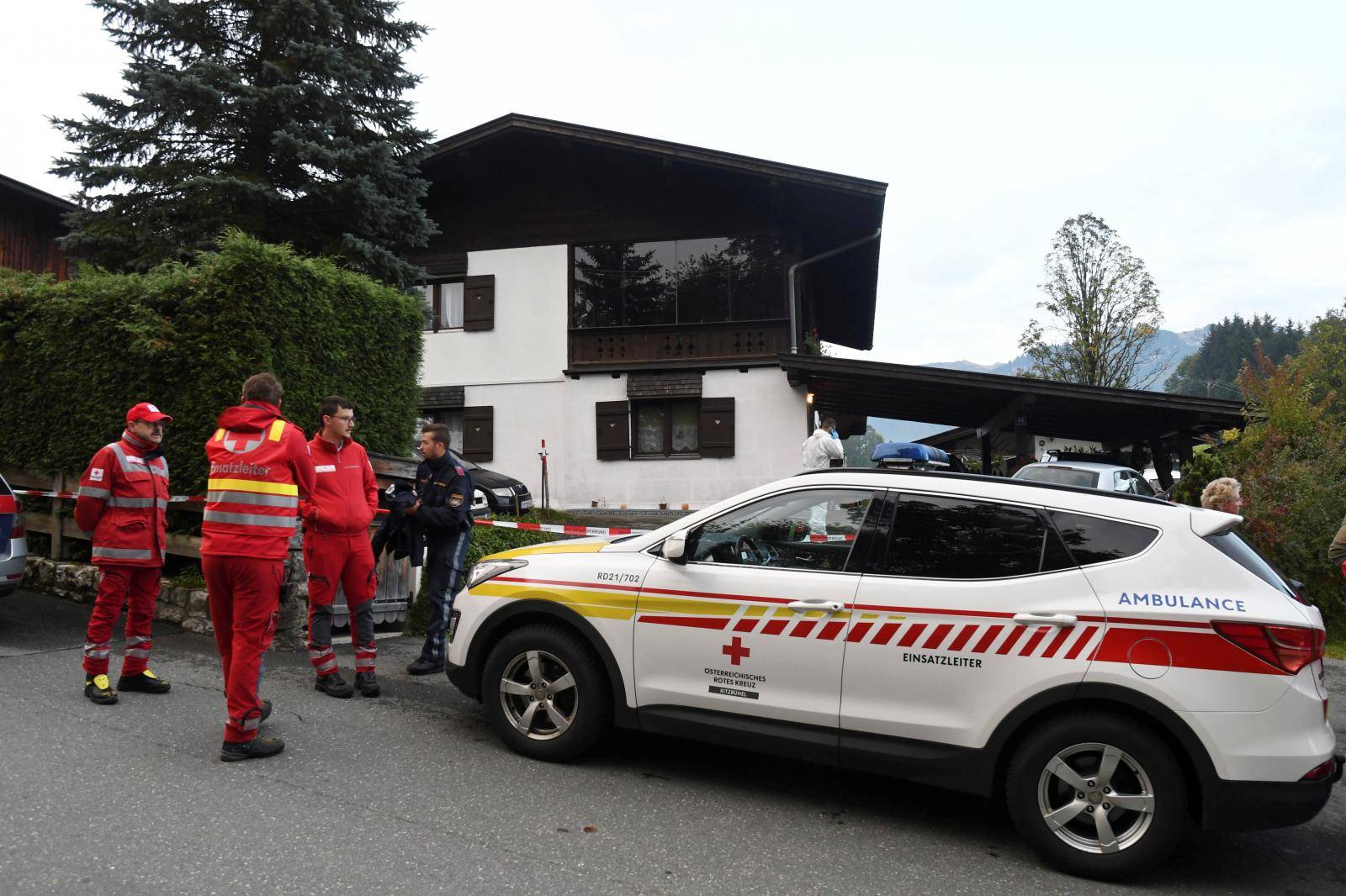Police officers and rescue workers stand in front of a house where, according to police, five people were found dead in Kitzbuehel