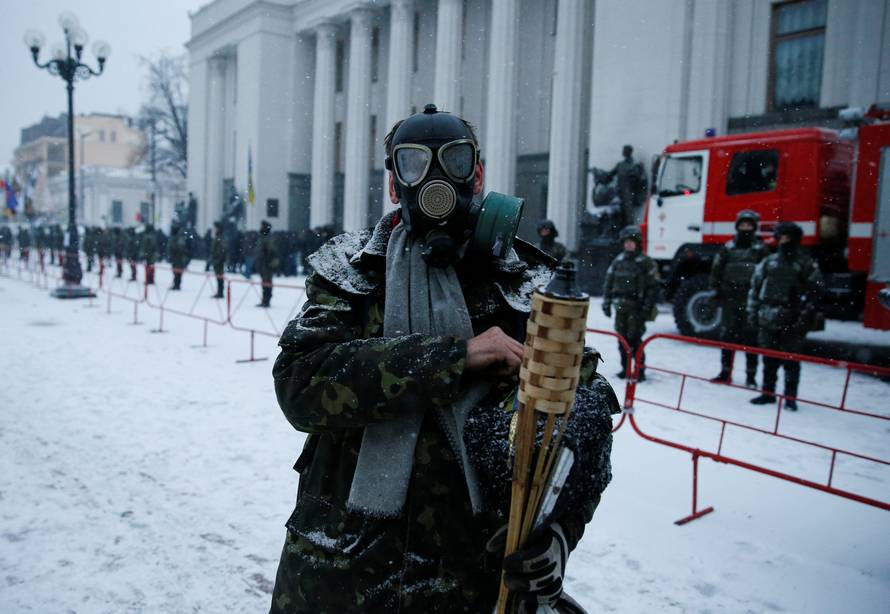 An anti-government protester wearing a gasmask stands in front of the Parliament building in Kiev
