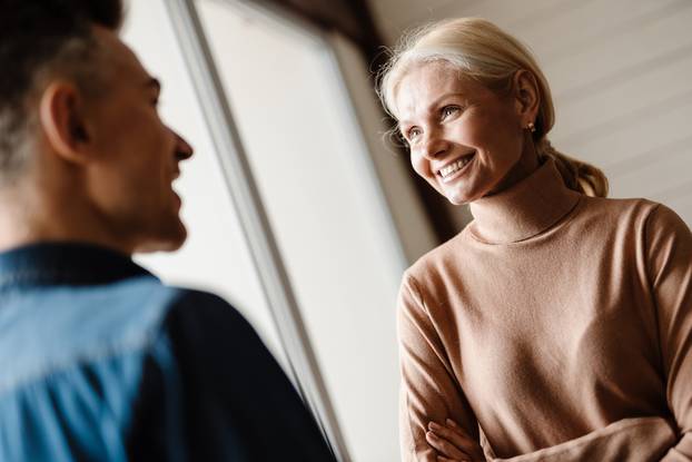 Happy mid aged white couple standing in modern living