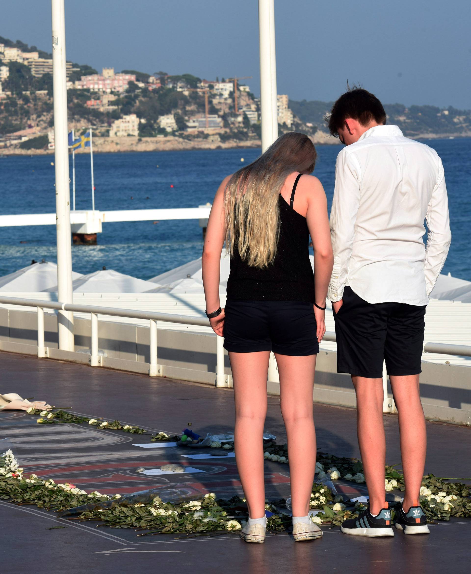 People look at a memorial with flowers, photos and texts to victims on the Promenade des Anglais as part of the commemorations of last year's July 14 Bastille Day fatal truck attack on the Promenade des Anglais in Nice