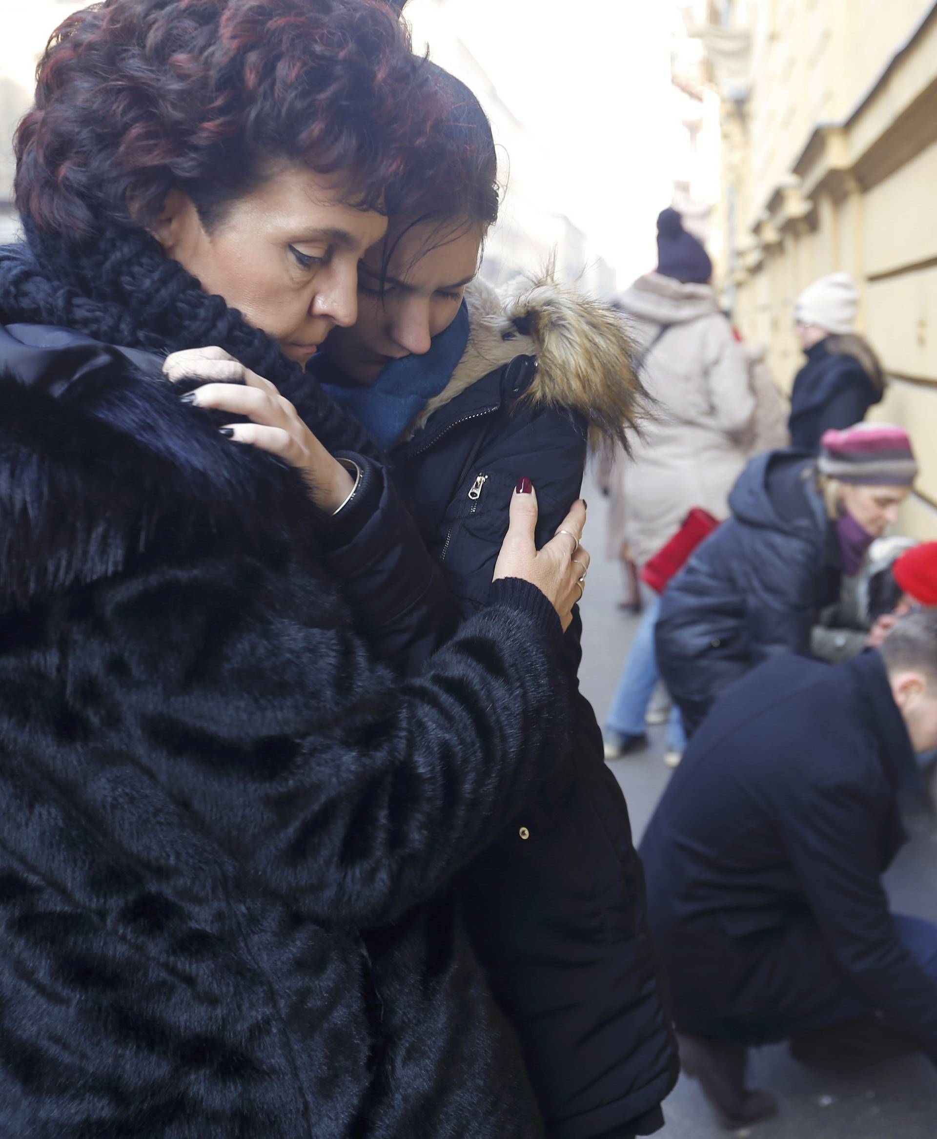 People comfort each other in front of a school building in Budapest