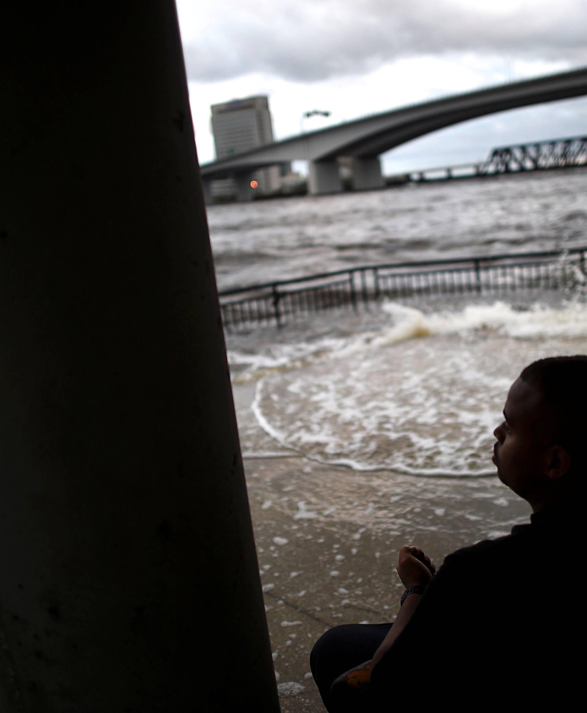Lui Nesbitt, 22, sits on a bench beside floodwaters after Hurricane Irma in Jacksonville