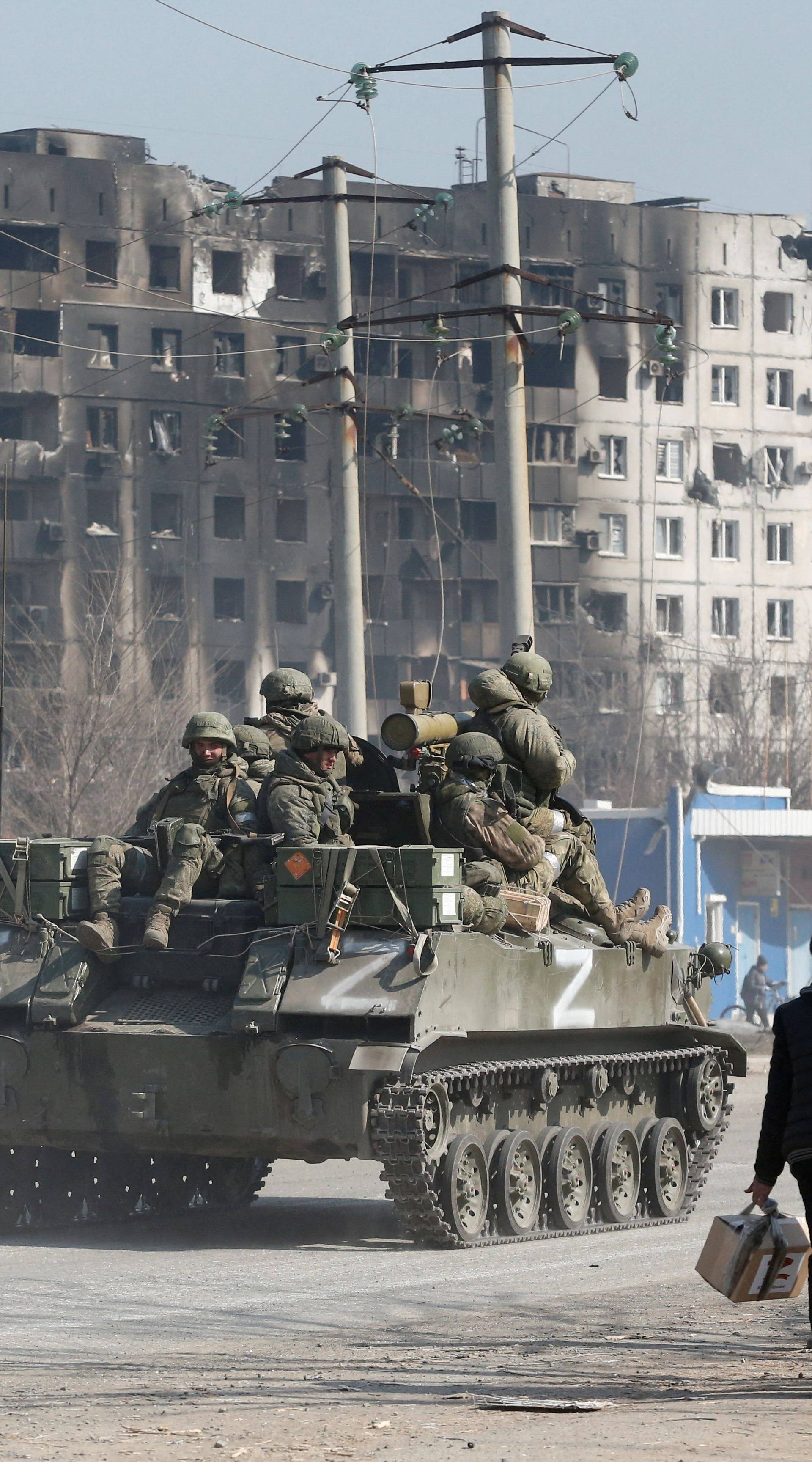 FILE PHOTO: Service members of pro-Russian troops are seen atop of an armoured vehicle in the besieged city of Mariupol
