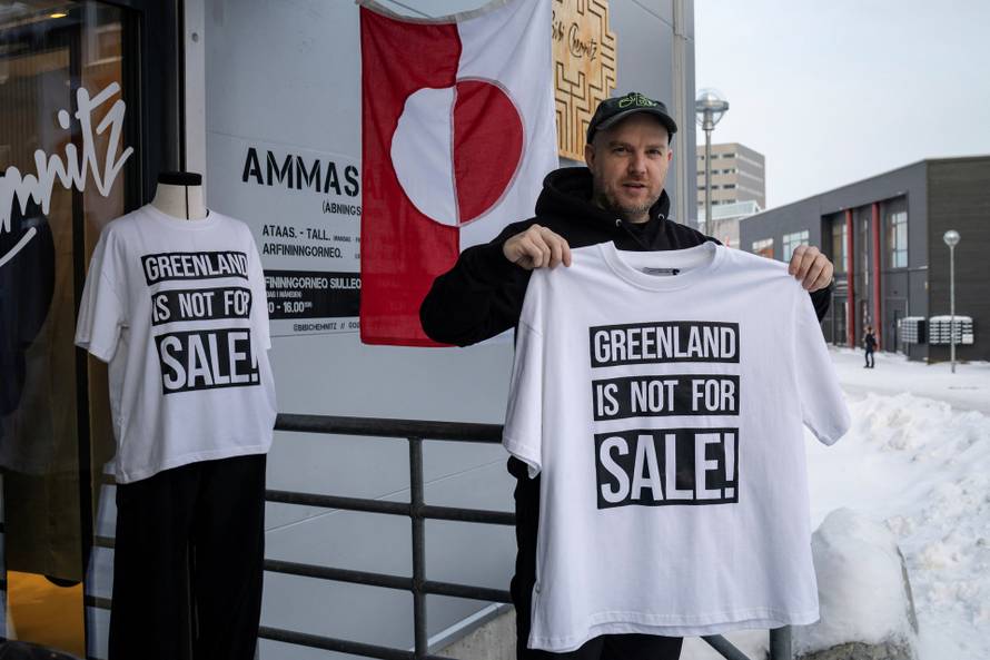 A shop owner David Rogilds holds a shirt that he sells in Nuuk