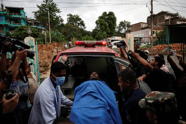 An injured man is rushed to a hospital for treatment following a flash flood at Trishuli, Nepal