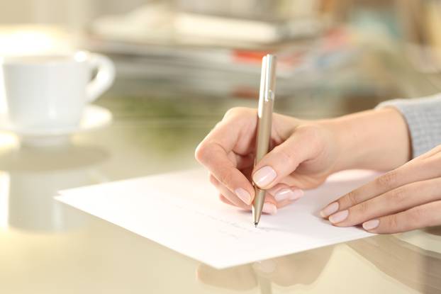 Woman hand writing on paper sheet