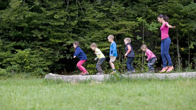 Kindergarten,Teacher,Playing,With,Kids,On,Log,In,A,Wood