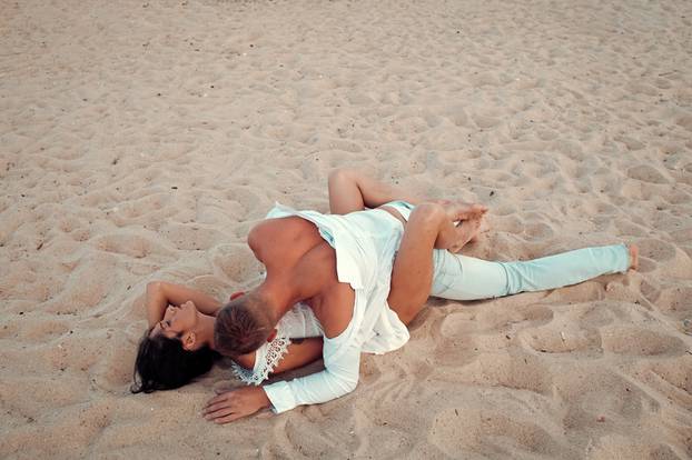 Honeymoon. Sex on beach concept. Couple full of desire have sex on sand of seashore. Sensual lovers making love at seashore. Couple in love have sex, makes love on sand beach