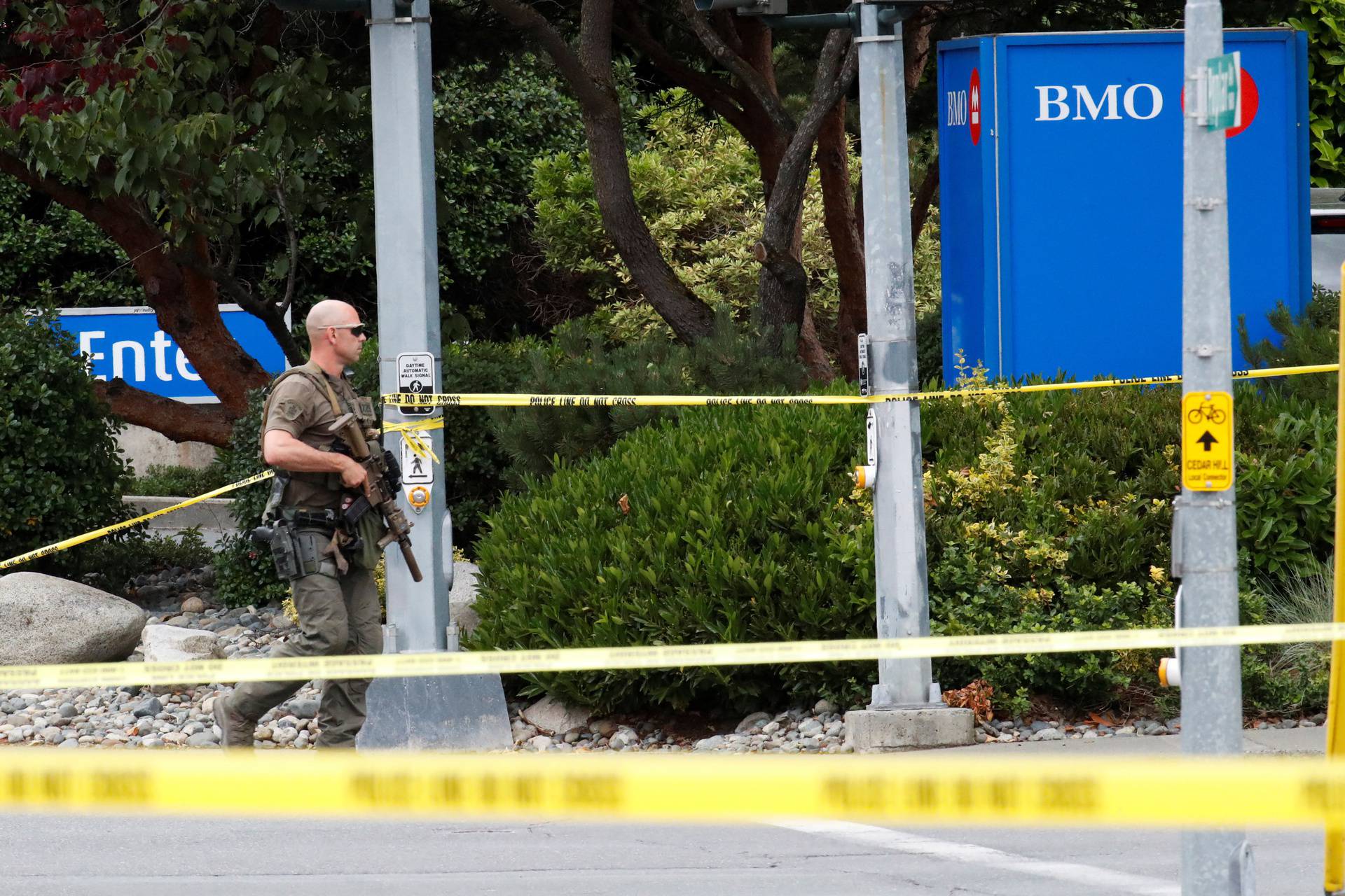 A police officer looks on after two armed men entering a bank were killed in a shootout with the police in Saanich