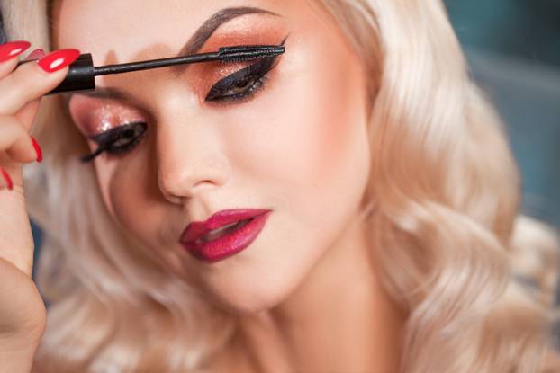 Beautiful young blonde makes a bright holiday makeup. Glamorous make-up.