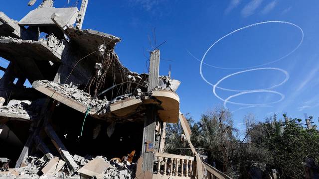 Israel aircrafts leave trails near the ruins of houses destroyed in Israeli strikes during the conflict, during a temporary truce between Hamas and Israel, in Khan Younis in the southern Gaza Strip