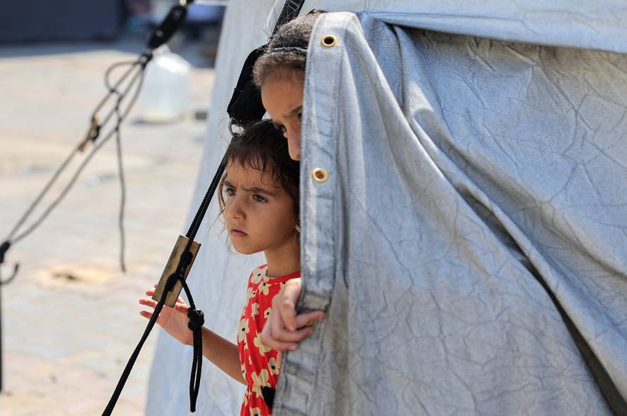 Displaced Palestinian children look out of a tent where they shelter, in Khan Younis, in the southern Gaza Strip