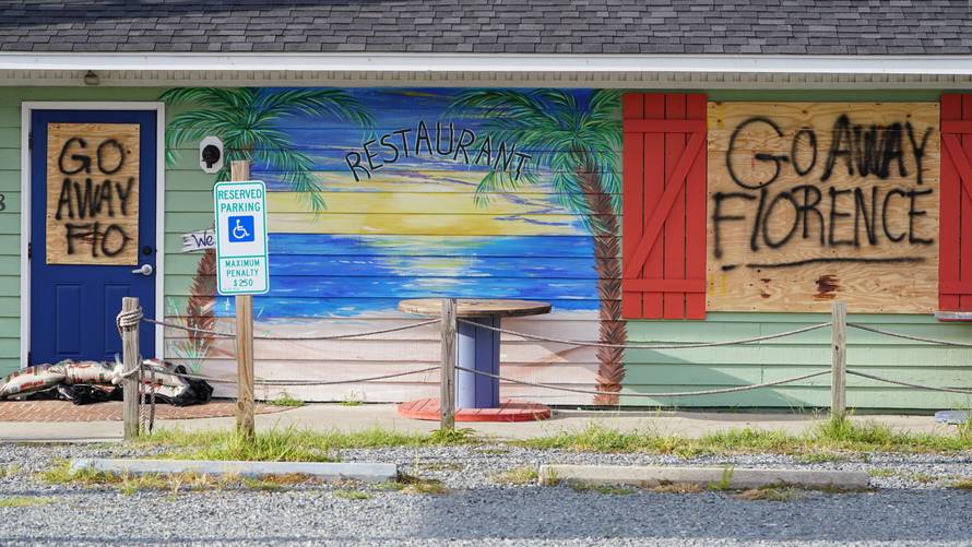 A sign is posted on a boarded up building before Hurricane Florence comes ashore on Oak Island