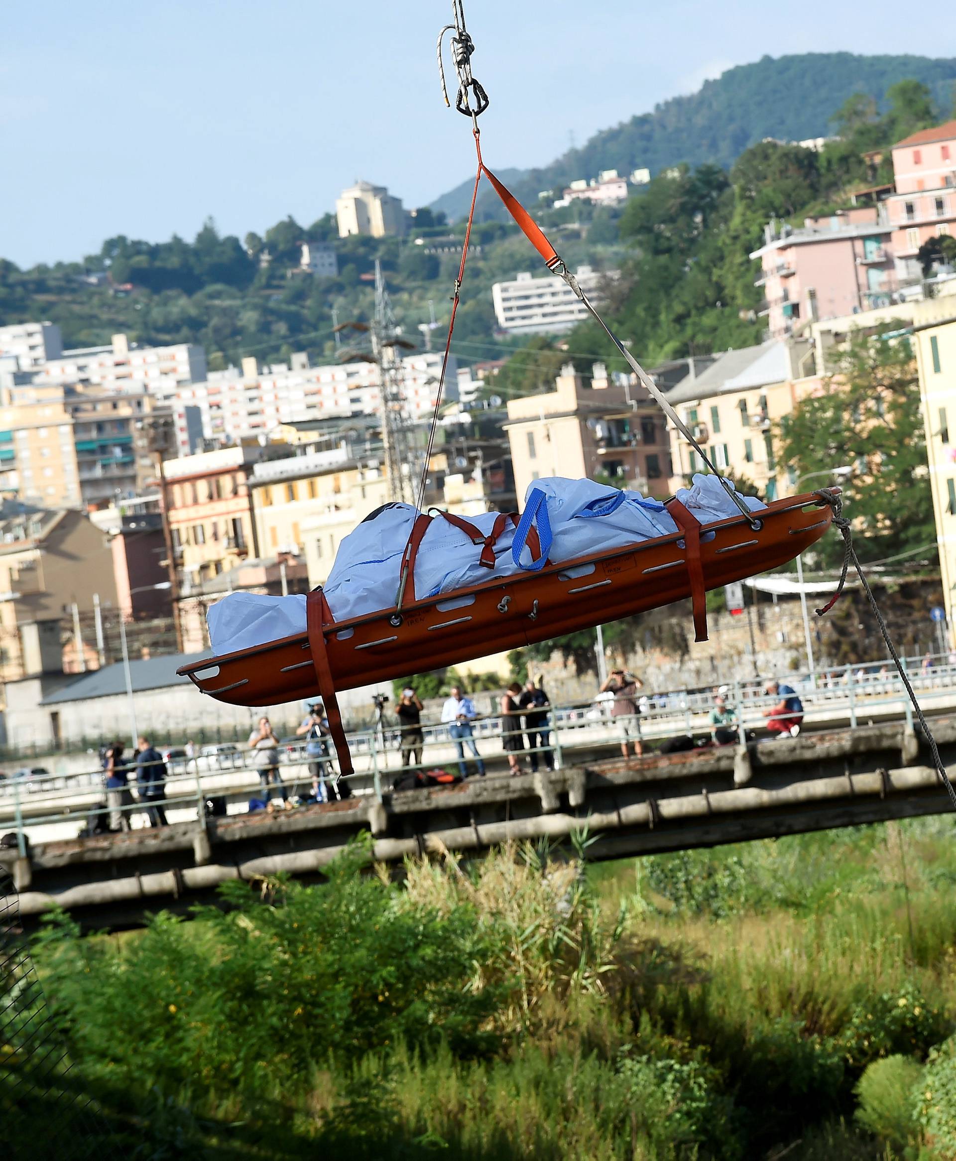 Rescue workers recover a body at the site of the collapsed Morandi Bridge in the port city of Genoa
