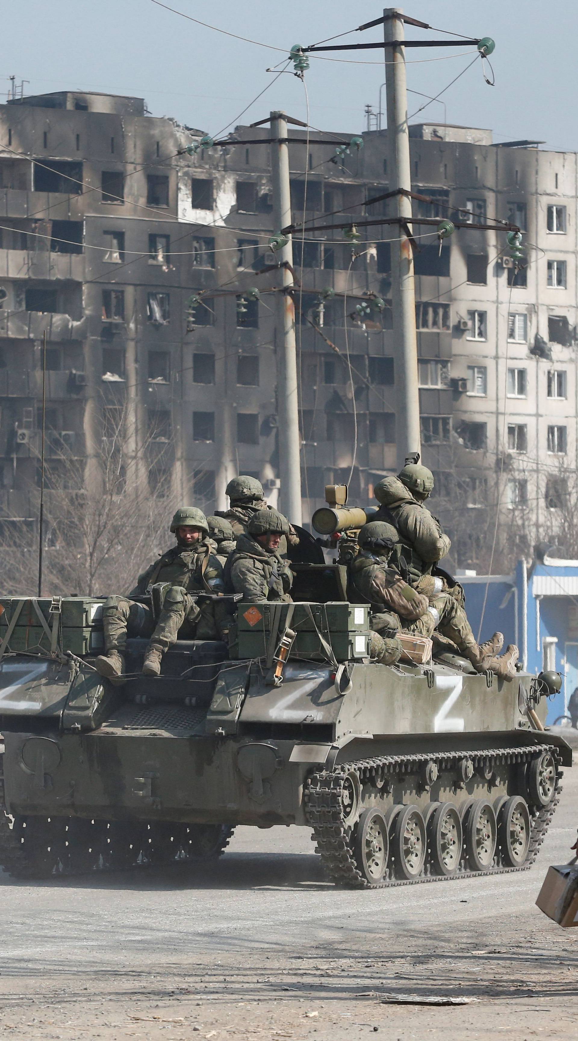 Service members of pro-Russian troops are seen atop of an armoured vehicle in the besieged city of Mariupol