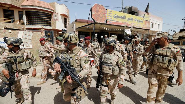 Iraqi army soldiers walk with their weapons in center of Falluja